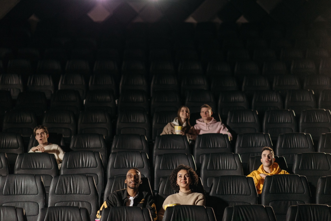 Personas observando el cartel de estrenos de cine en una sala de Cine Colombia antes de ingresar a una función de fin de semana.